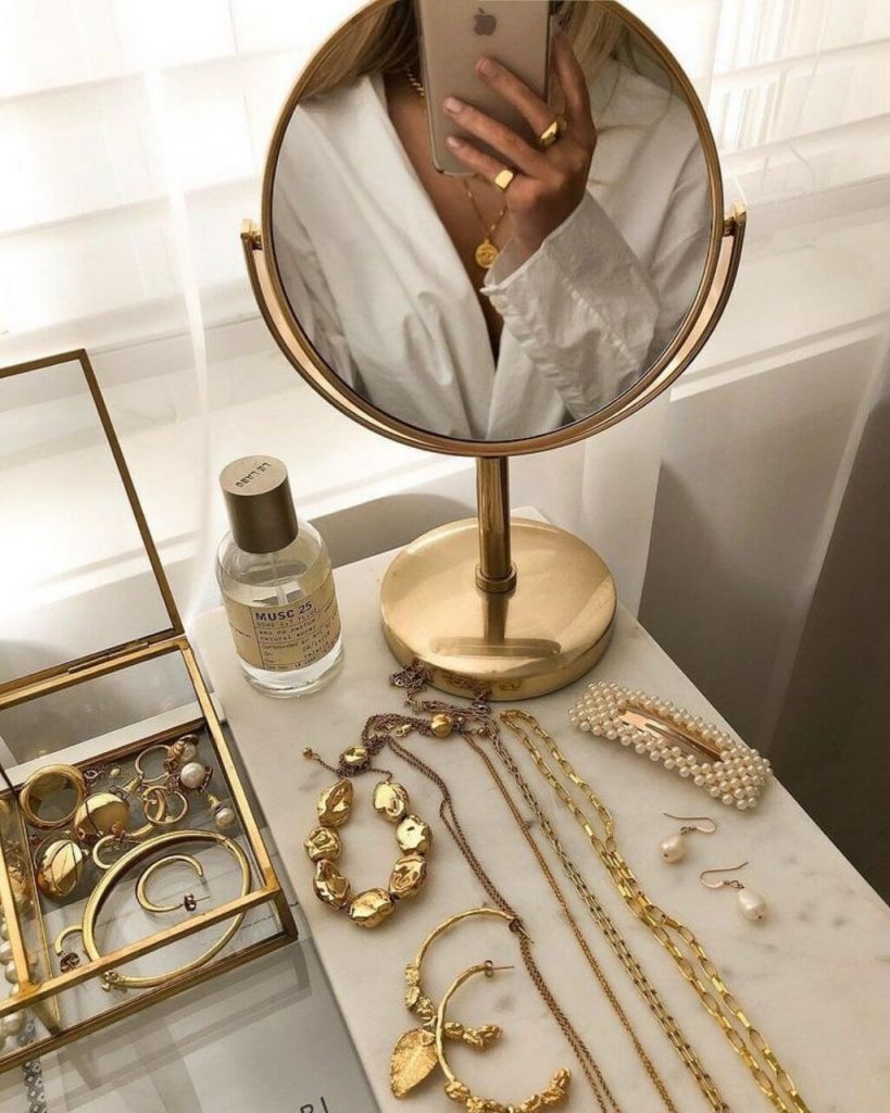 Une fille qui prend une photo dans le miroir avec des bijoux en or