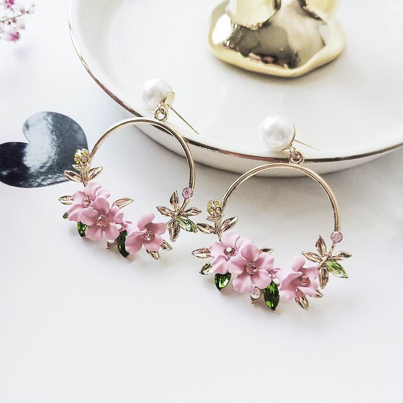 Une paire de boucle d'oreille qui est décoré de fleur rose